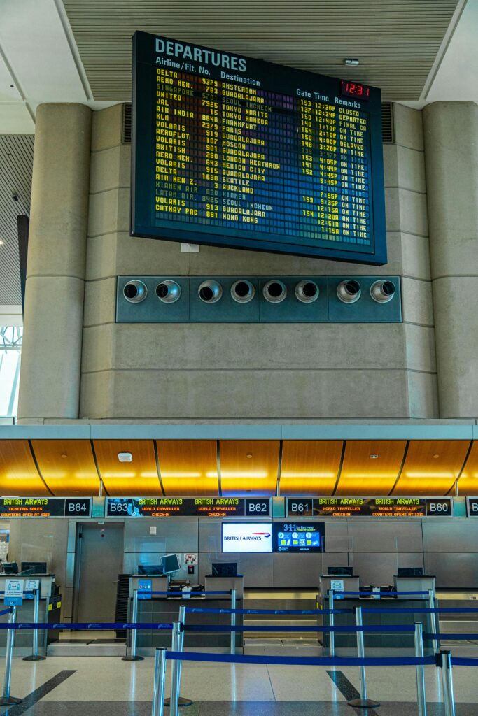 Digital departure board and airline check-in counters inside a modern airport terminal.